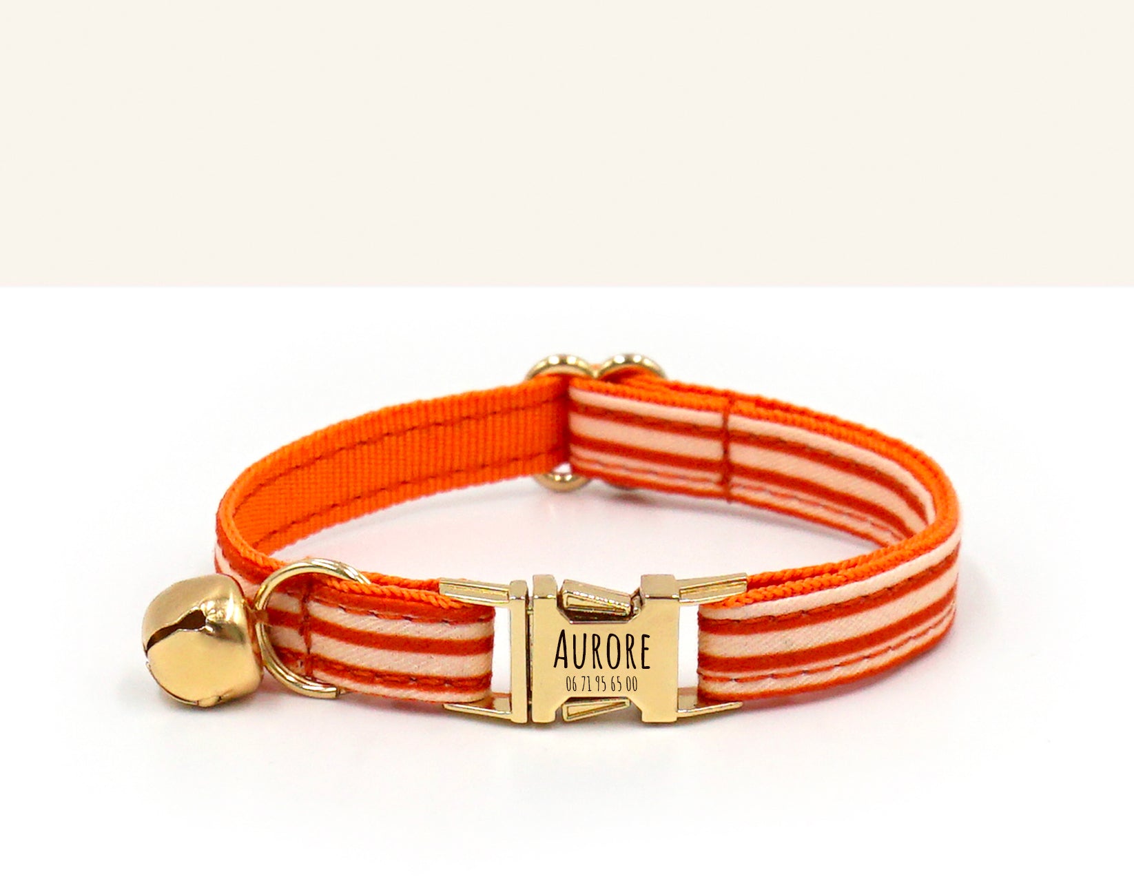 Collier chat personnalisé coton rayé orange avec fermoir doré et petit pendentif cloche, nom Aurore gravé sur plaque.