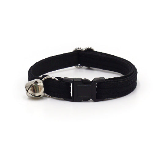 Collier chat anti-étranglement en velours côtelé noir avec fermoir plastique et petit charme métallique.